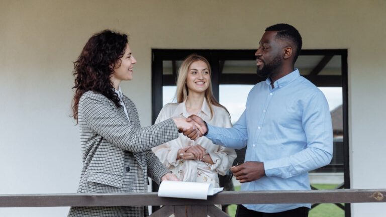 Drie mensen bij een woning, twee schudden handen na succesvolle bezichtigingen